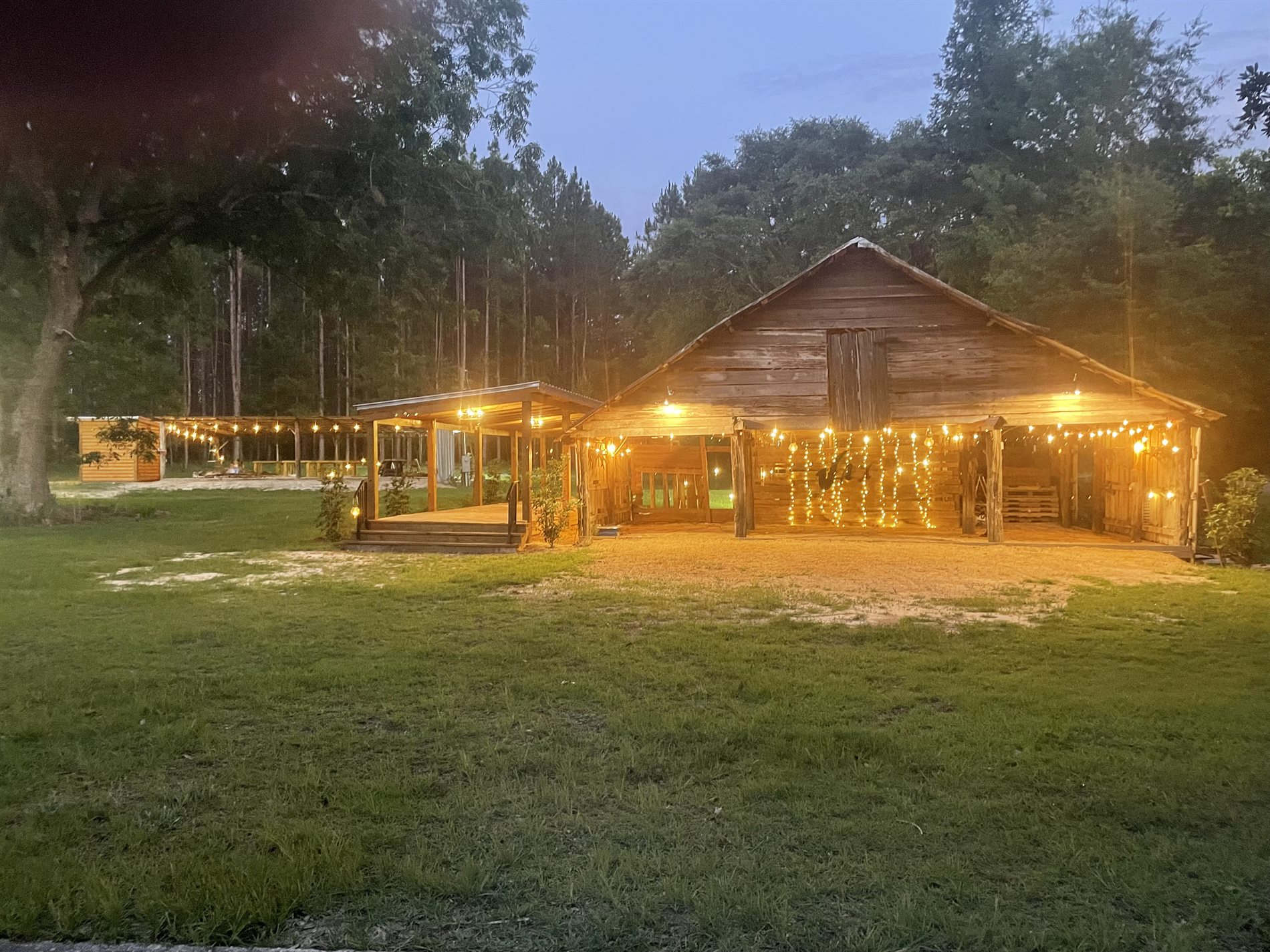 Wide dusk view of historic cypress barn with string lights for rustic weddings