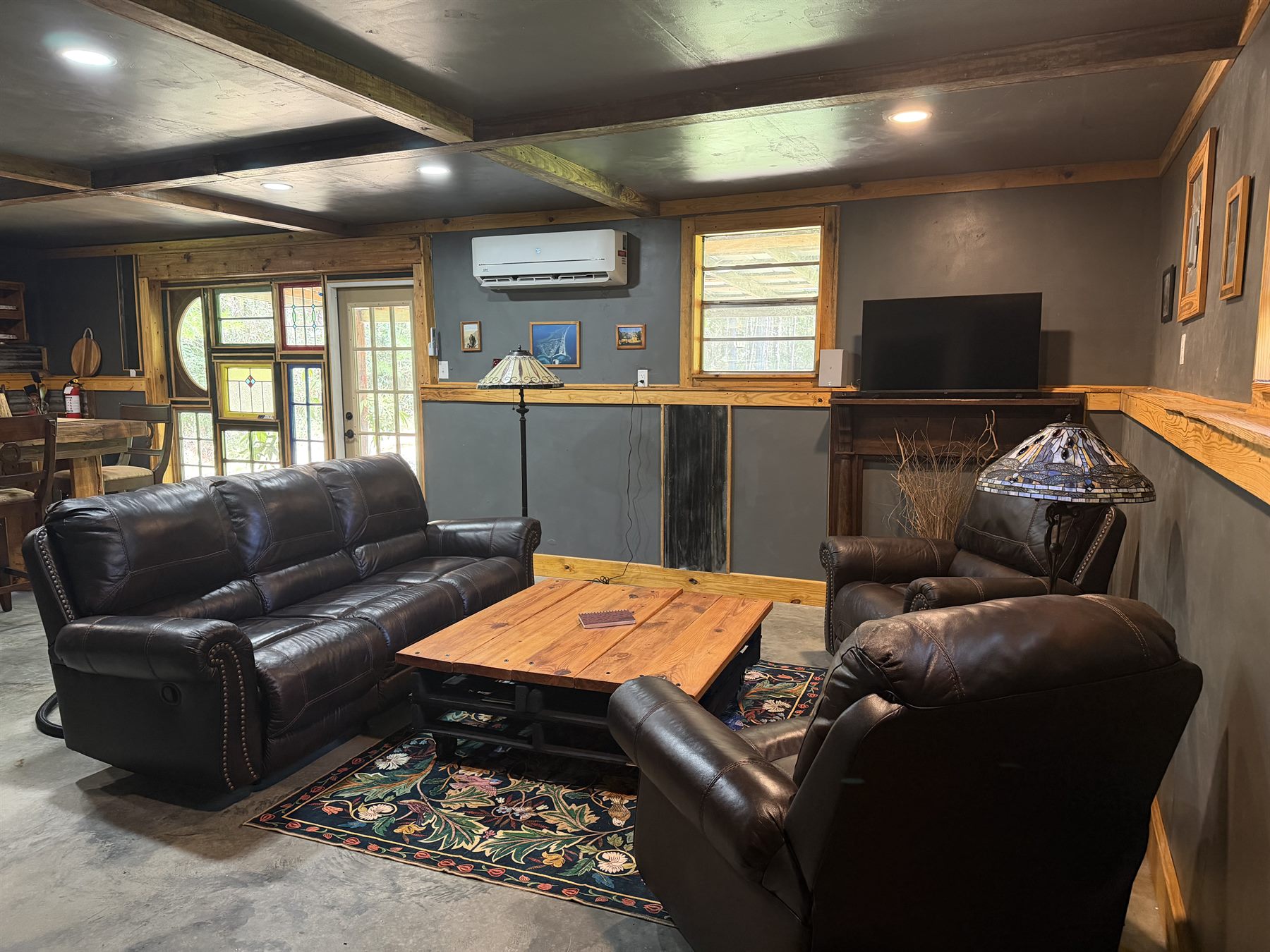 Cabin interior living room with leather seating, TV and rustic custom wood details at Rustic JaxFarm