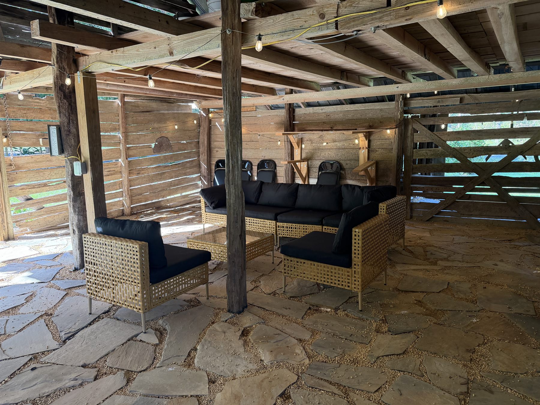 Historic barn living room seating area with flagstone floor and rustic lounge furniture at Rustic JaxFarm in South Alabama